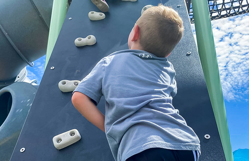 Youngster climbing on-new playground jungle gym