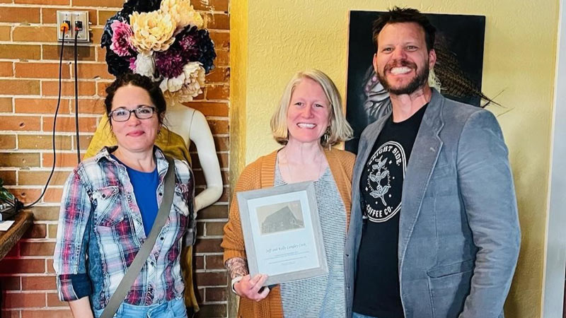 Historic Preservation Commission Chair Christen DePetro stands next to Kelly Langley Cook and Jeff Cook. Kelly holds up the award for rehabilitating the Ambry