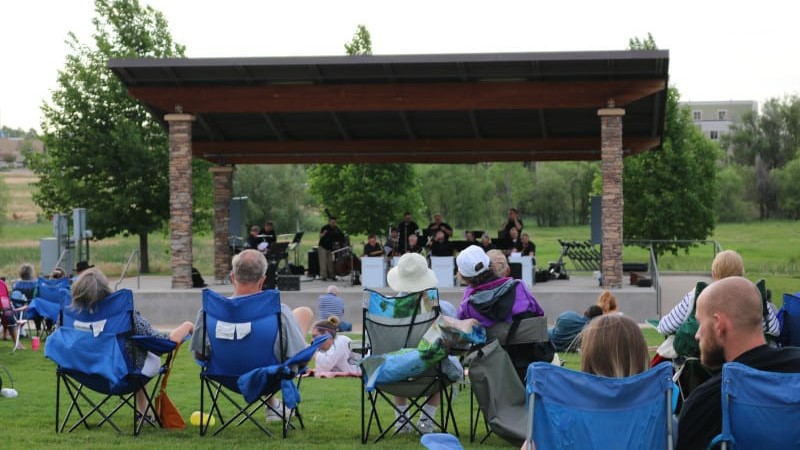 People sit in lawn chairs on the grass watching a concert at the Family FunPlex amphitheater.