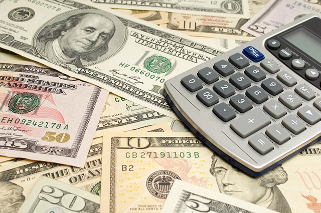 Image of American currency bills scattered on a table with a calculator